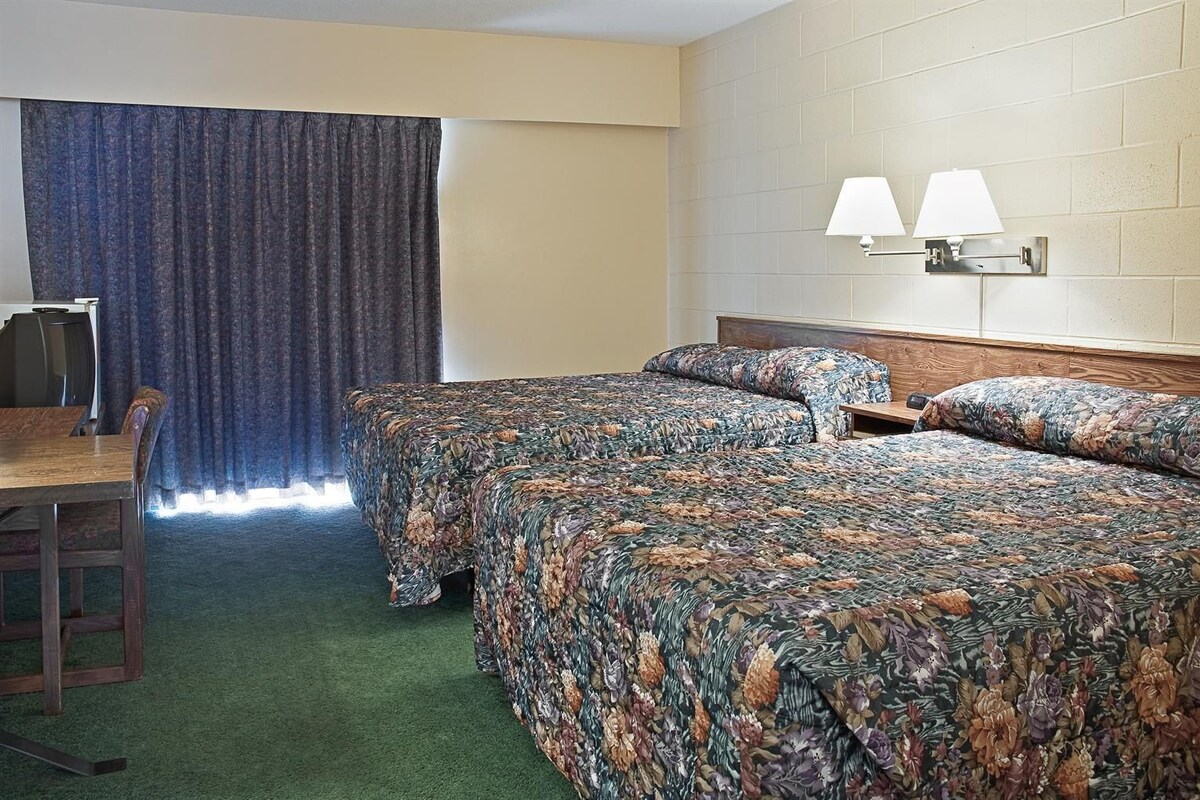 A hotel room with two beds, a desk, and a chair.