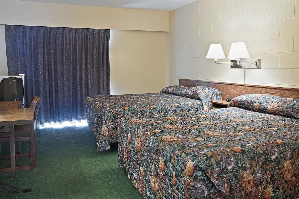 A hotel room with two beds, a desk, and a chair.