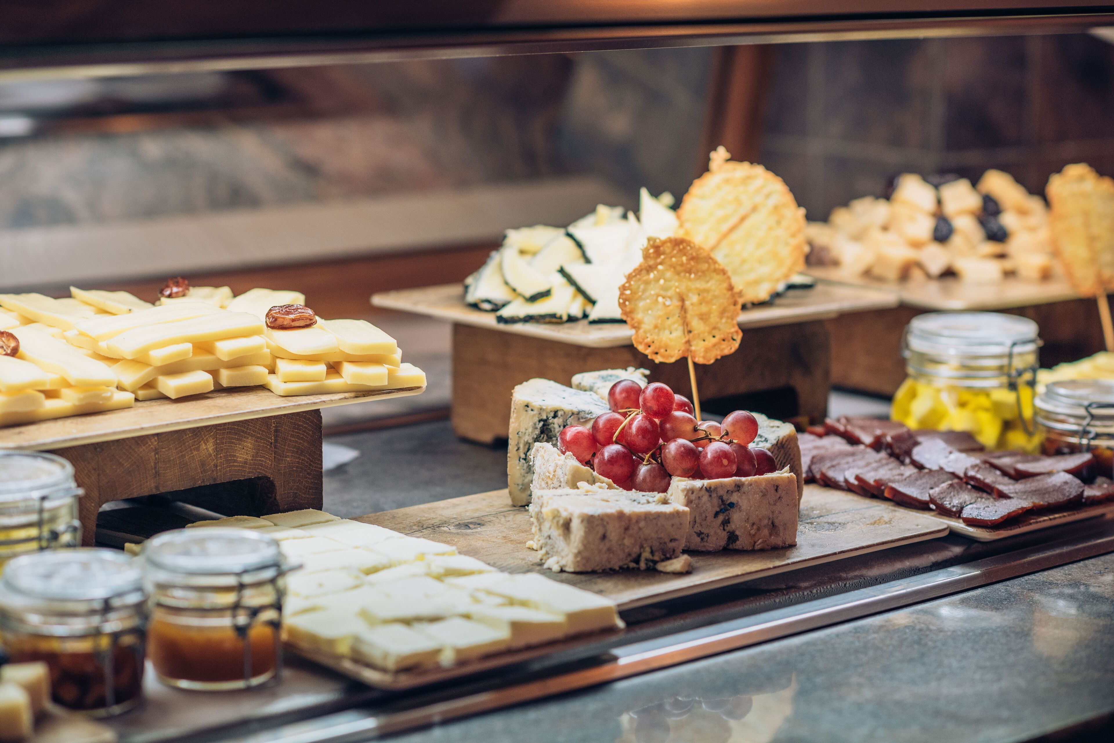 Un plateau de fromages et de charcuteries, avec différents types de fromages, des raisins et des crackers.