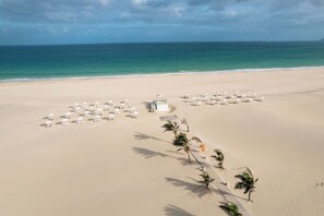 Am Strand, weißer Sandstrand, Liegestühle, Sonnenschirme