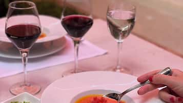 A dining table with a bowl of soup, a fork, and two wine glasses.