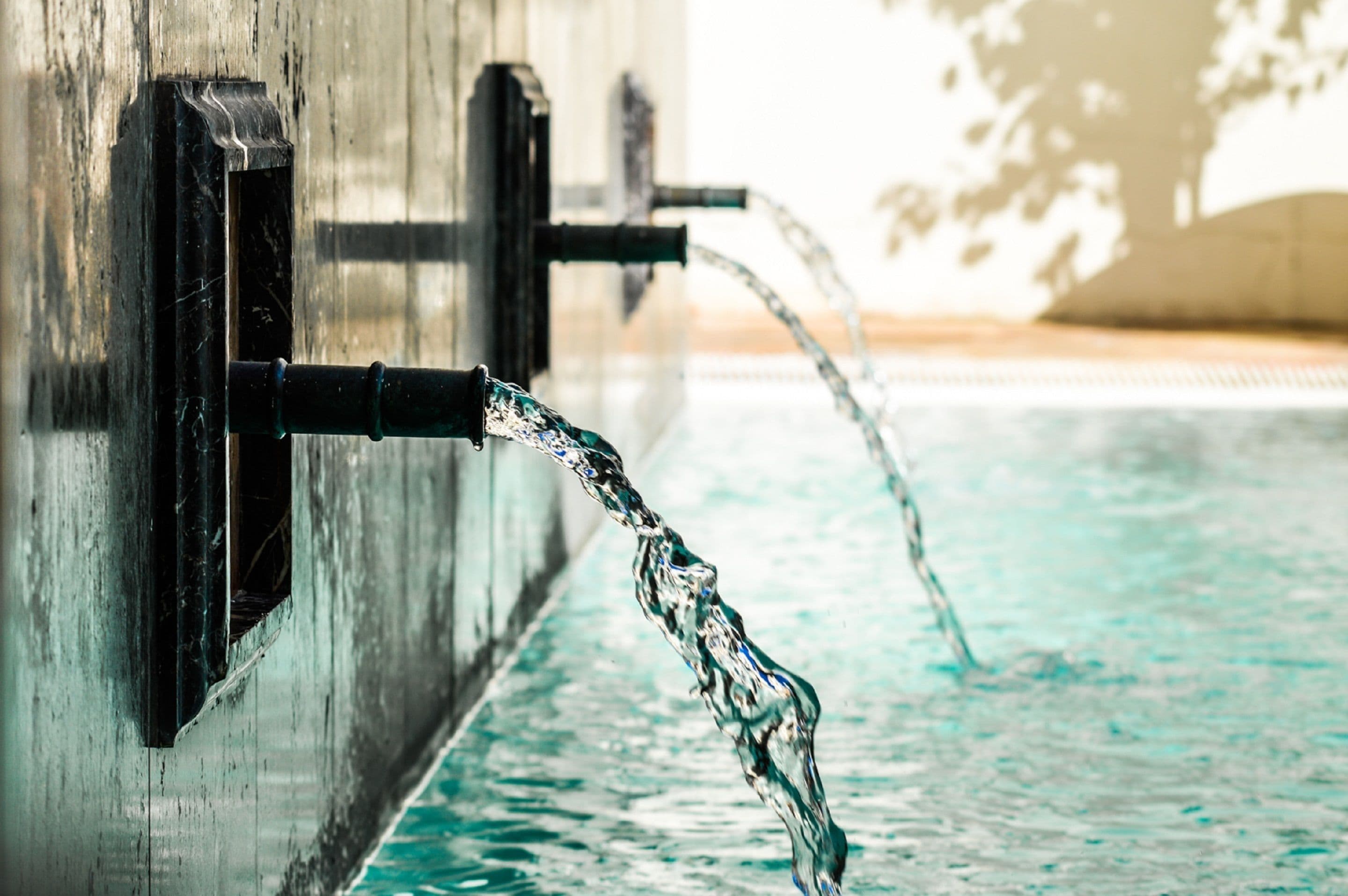 A pool with clear water and a faucet.