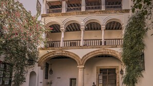 Un patio con un arco central, bancos y una persona de pie.