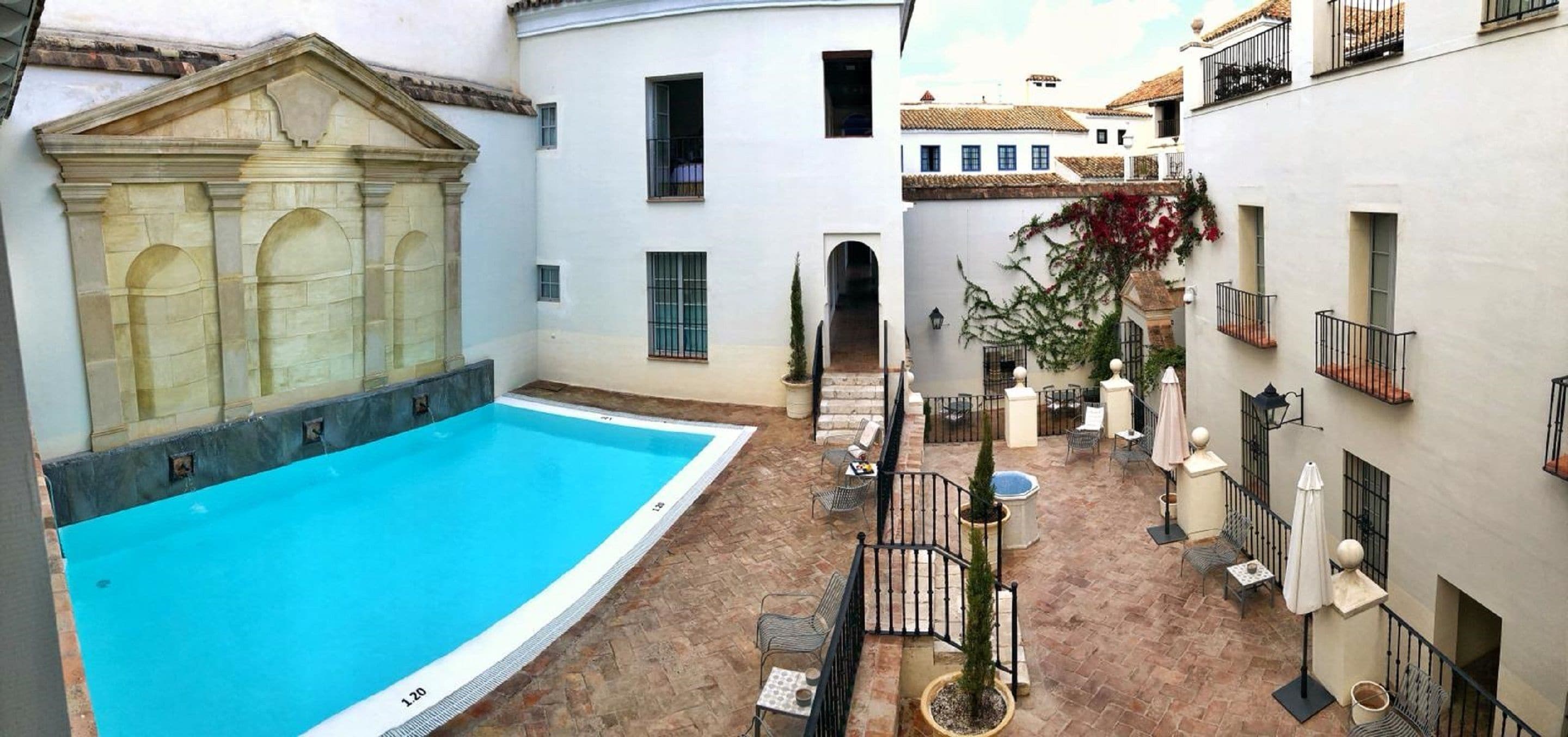 A courtyard with a swimming pool, outdoor seating, and traditional architecture.