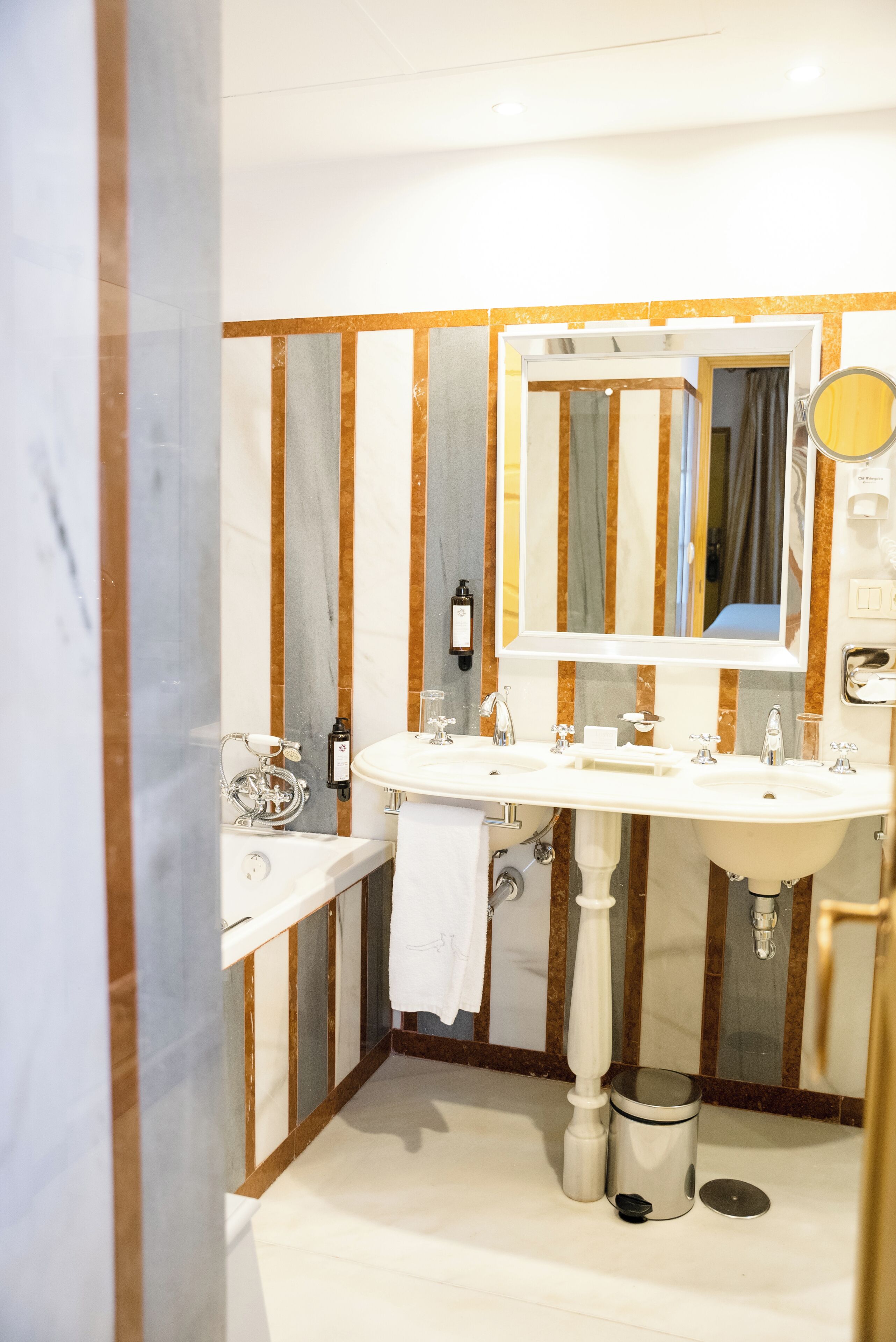 A bathroom with a double sink, a bathtub, and a mirror.