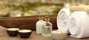 A wooden tray with rolled white towels, two small bowls, and two glass bottles with cork stoppers.