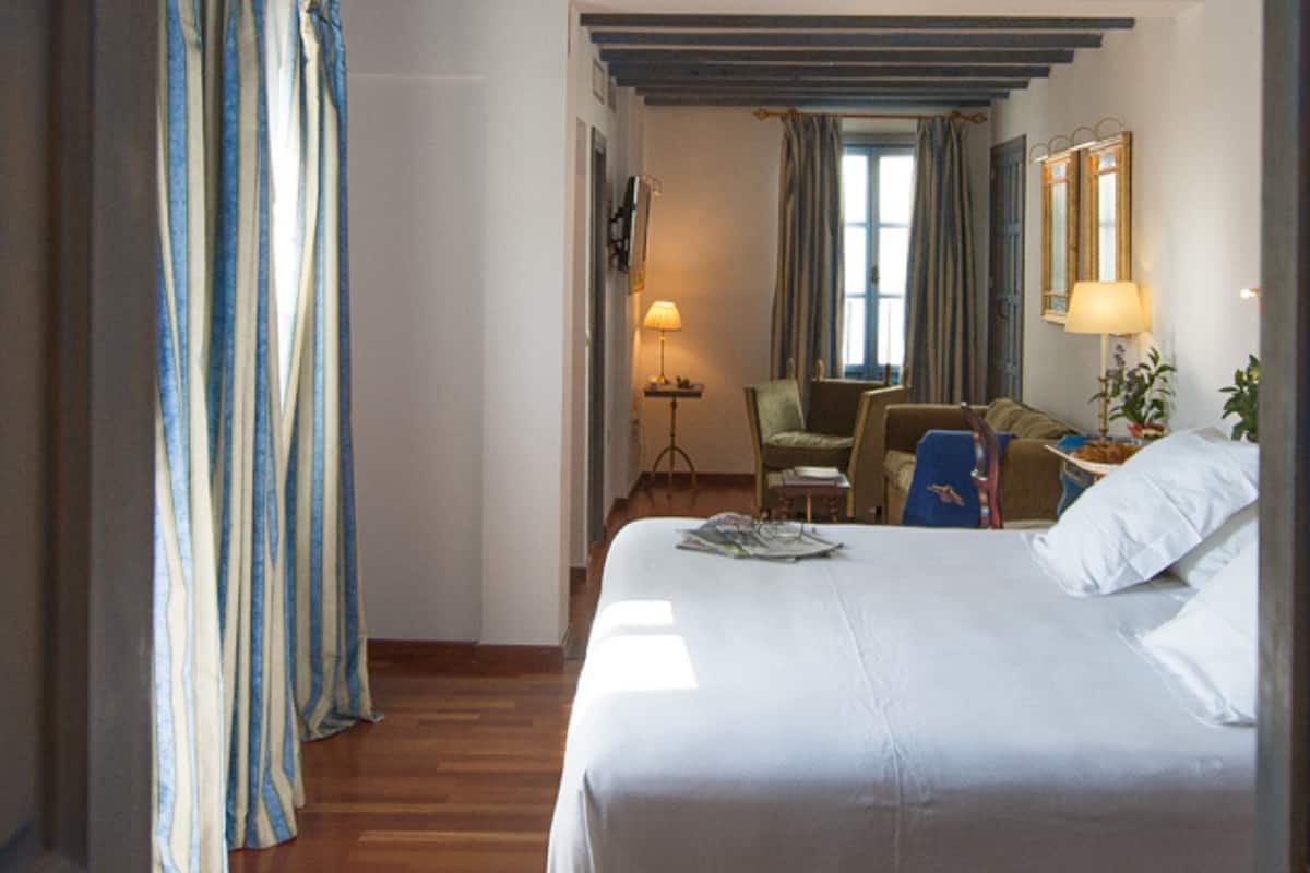A hotel room with a bed, a desk, a chair, and a window with curtains.