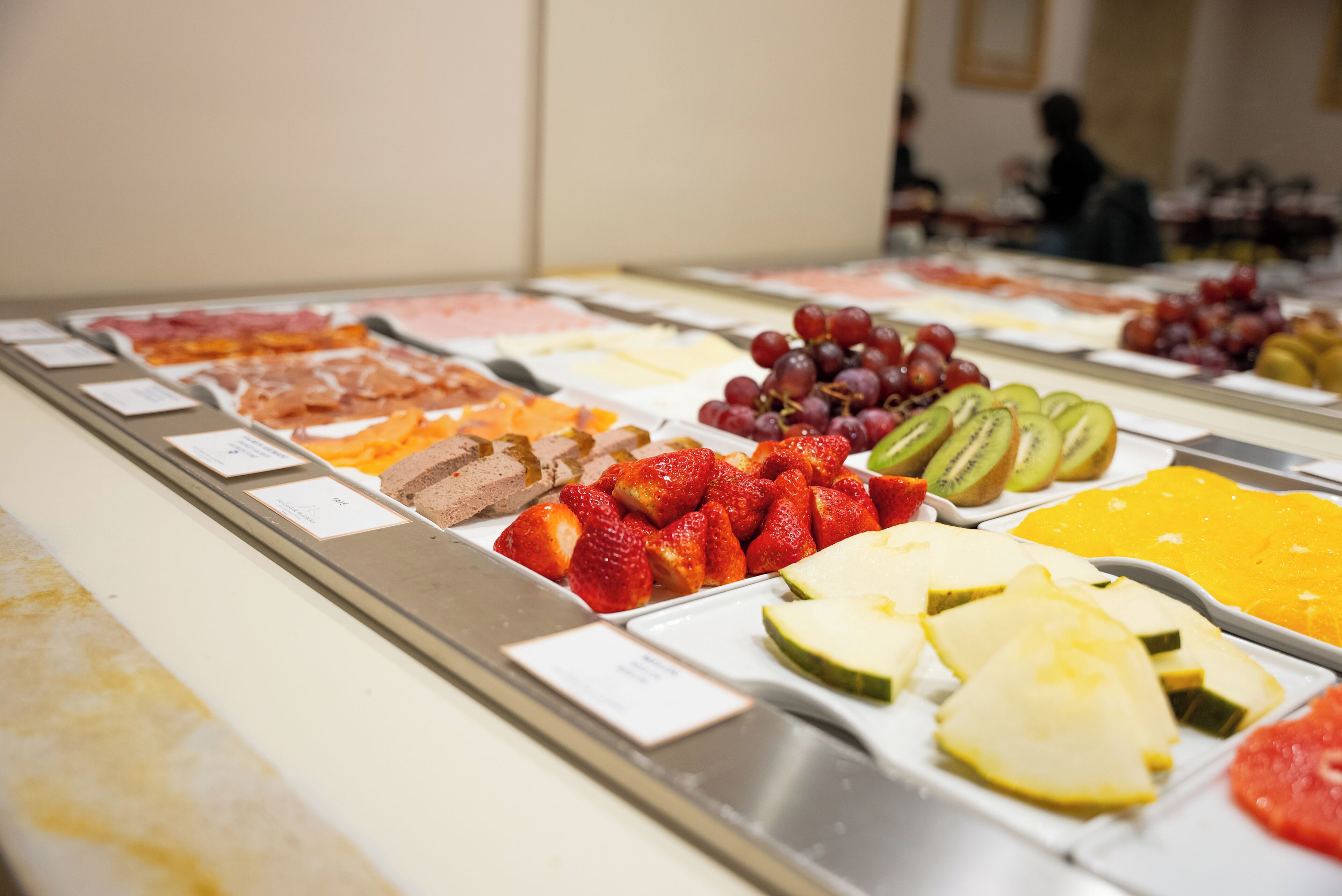 A buffet with various food items including fruits, cheeses, and meats.