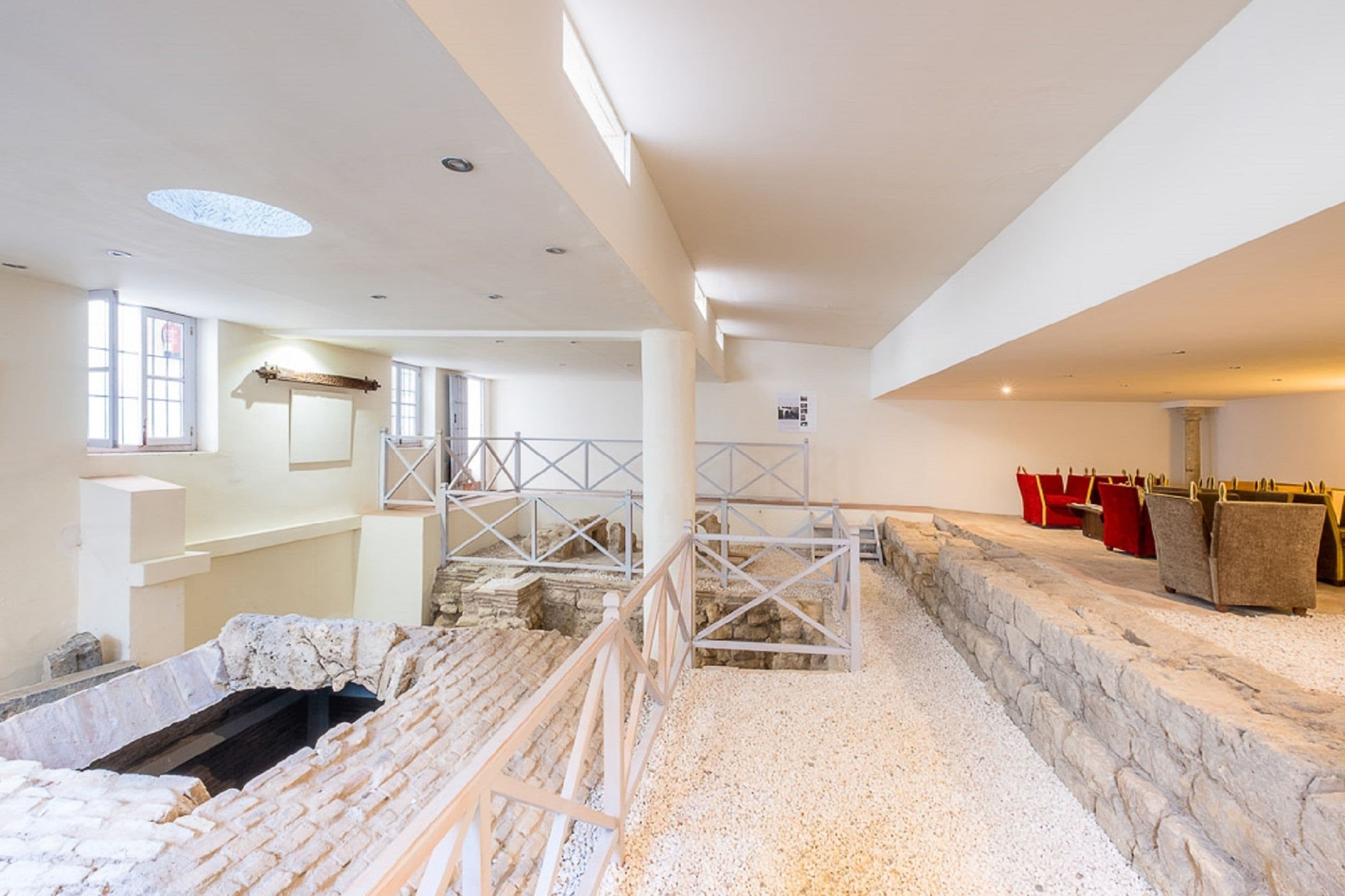 An interior with a stone floor, white walls, and a staircase leading to an upper level.