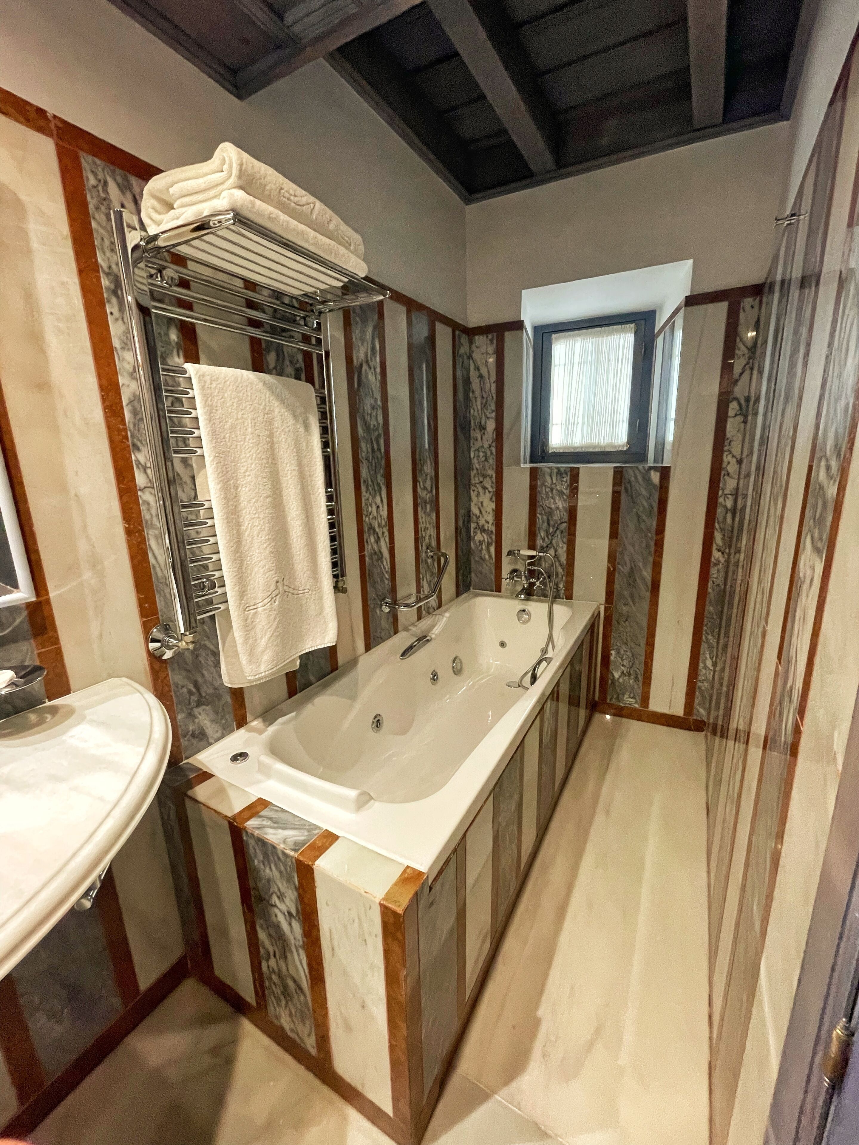 Un baño con una bañera grande, un lavamanos y una ventana.