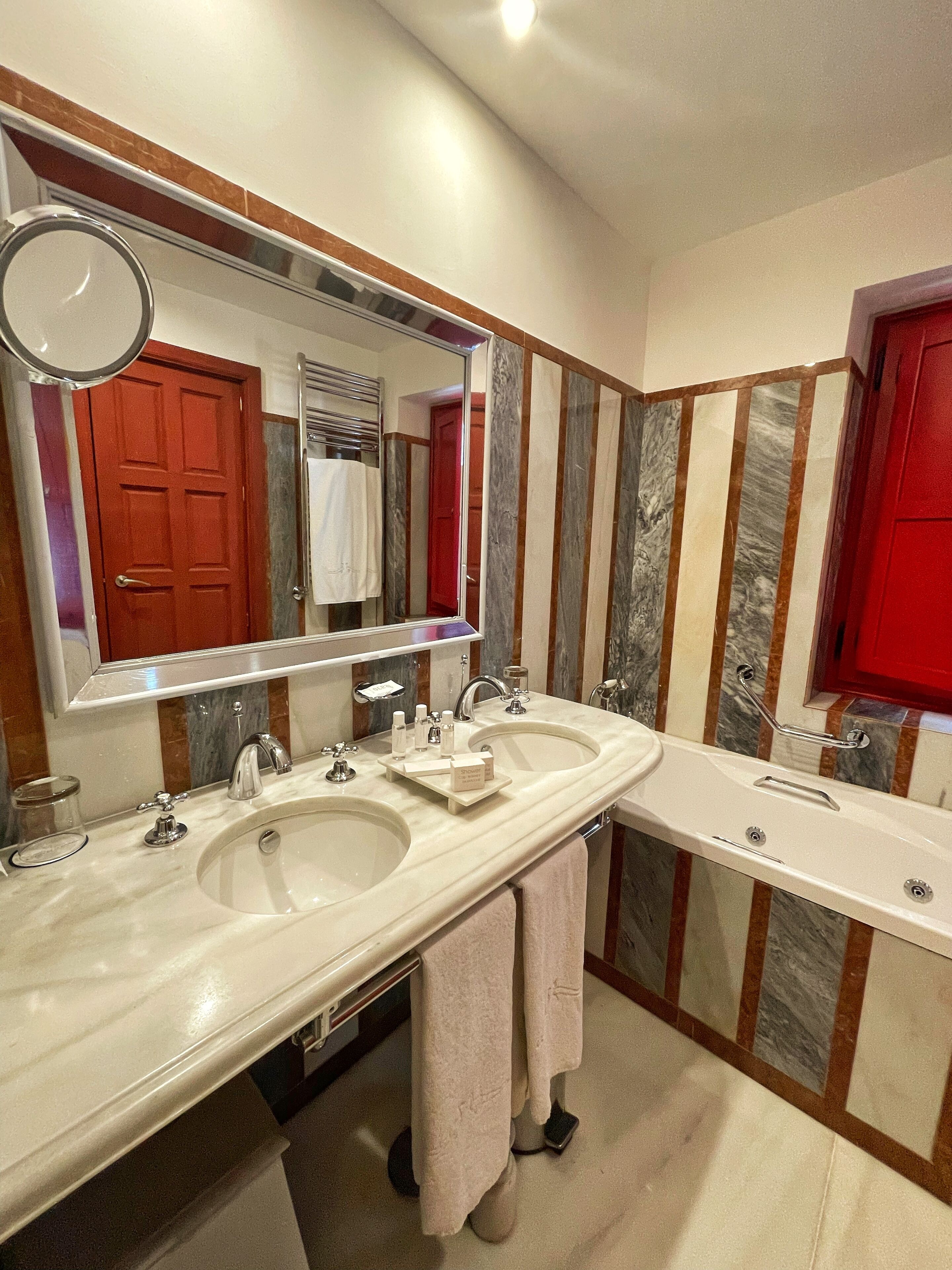 A bathroom with two sinks, a large mirror, and a red cabinet.