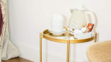 Una mesita redonda con una taza blanca y una tetera de estilo antiguo.