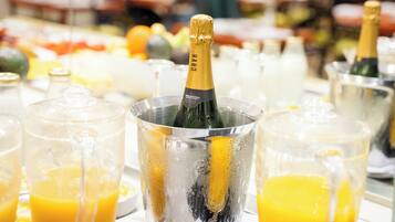 Een champagnefles in een metalen emmer, omringd door glazen jus d'orange.