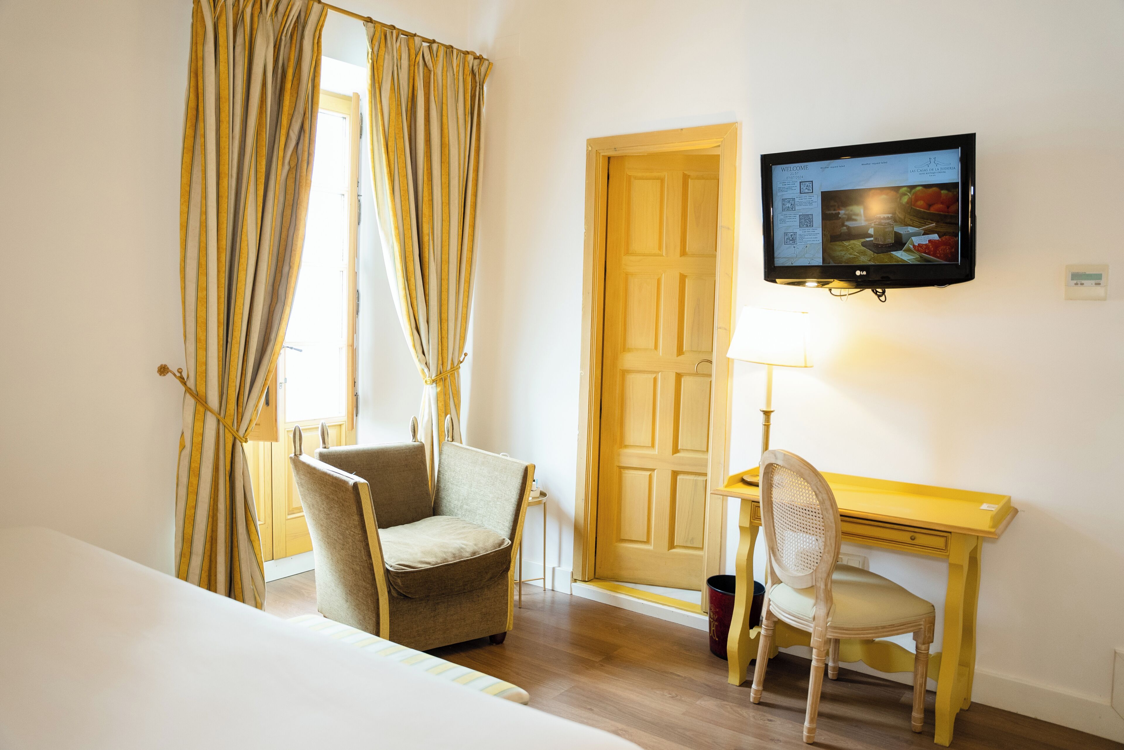 Une chambre d’hôtel comprenant un lit, un bureau, une chaise, un téléviseur fixé au mur et une porte.