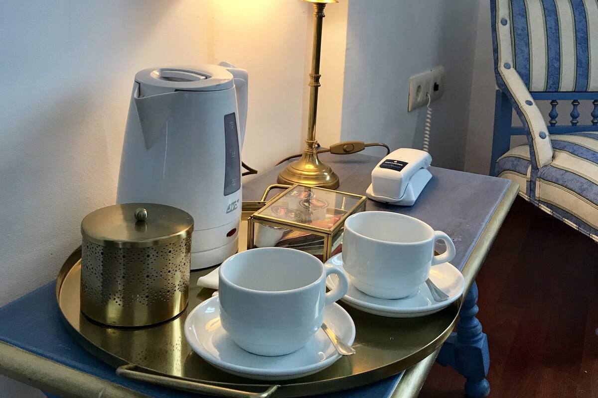 A tray with a coffee maker, a lamp, and two cups on a table.