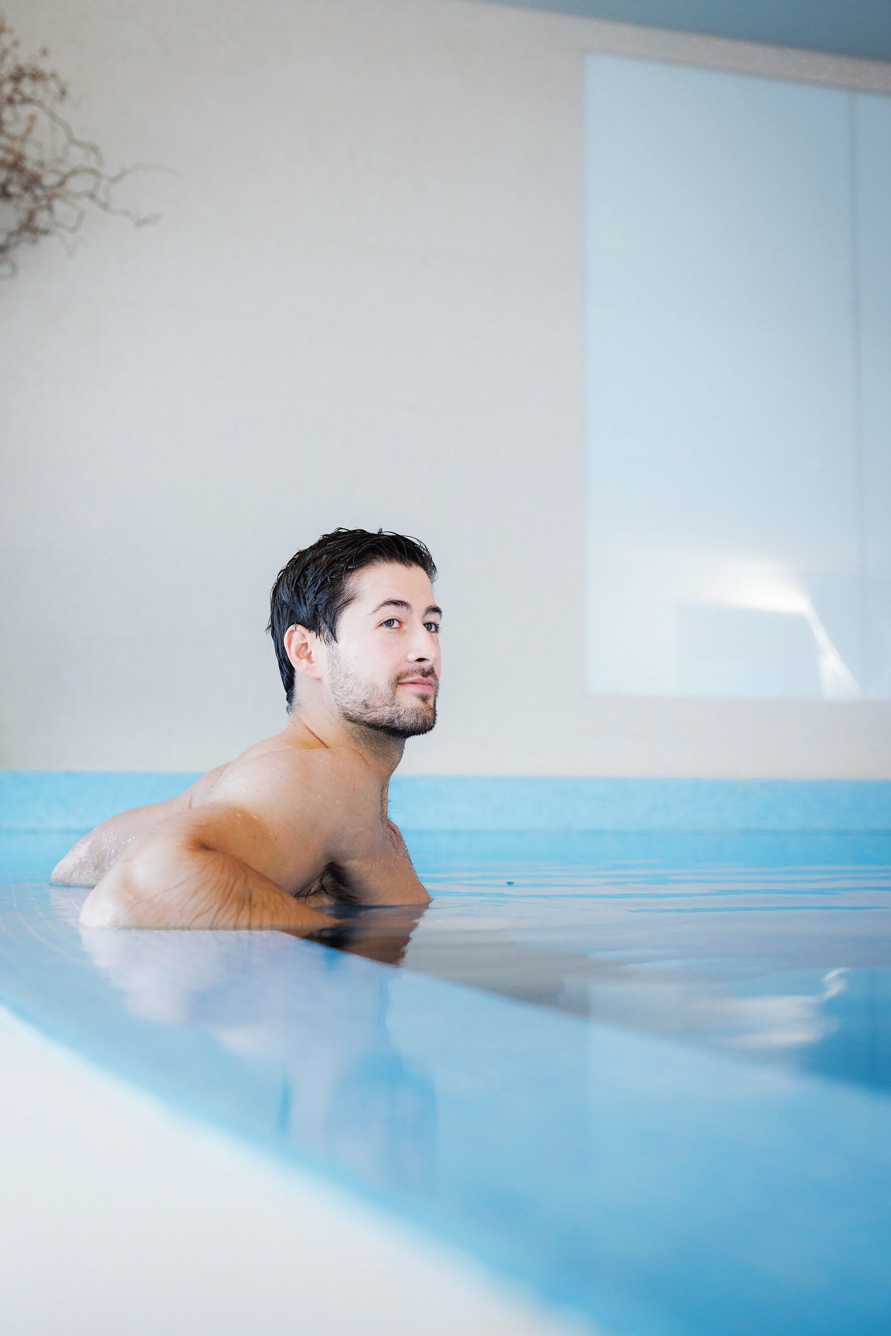 Una persona en una piscina, con vista clara al borde y una ventana al fondo.