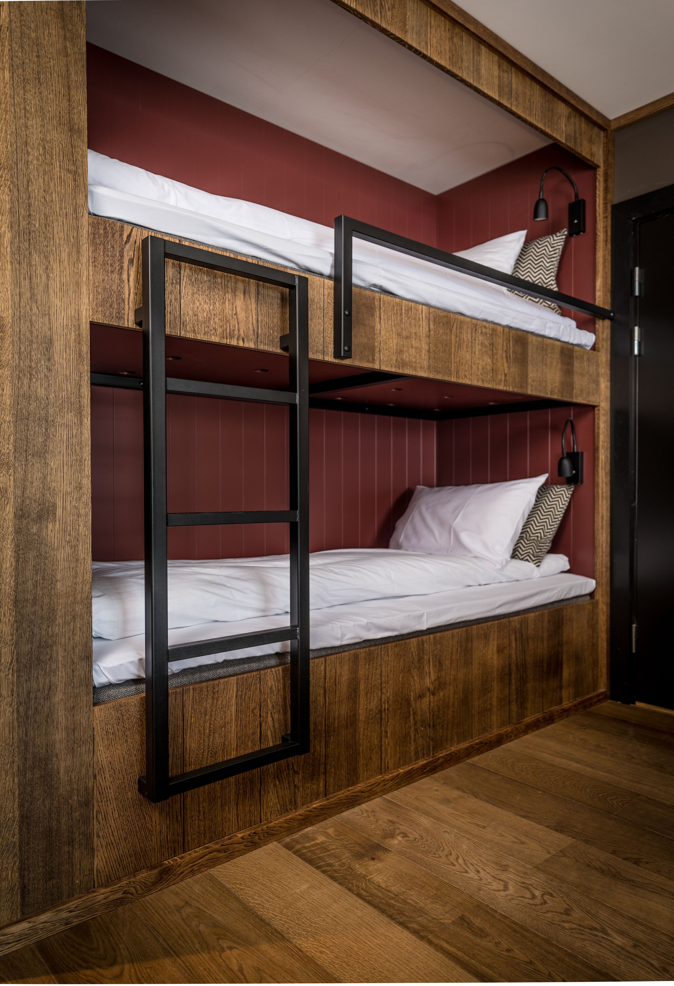 Een stapelbed met een houten frame en rode wanden.