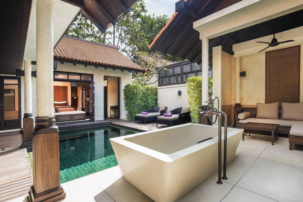 A spa area with a large bathtub, outdoor seating, and a pool.