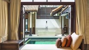 A luxurious bathroom with a large bathtub, a glass-enclosed pool, and a view of a traditional architectural structure.