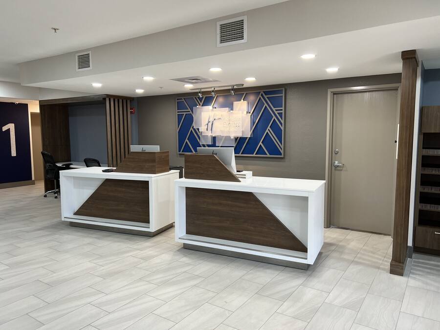 Un espace d’accueil comprenant deux comptoirs de réception blancs, une décoration murale géométrique bleue et une porte portant le numéro « 1 ».