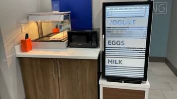 A self-service breakfast station with a digital menu display listing yogurt, eggs, and milk.