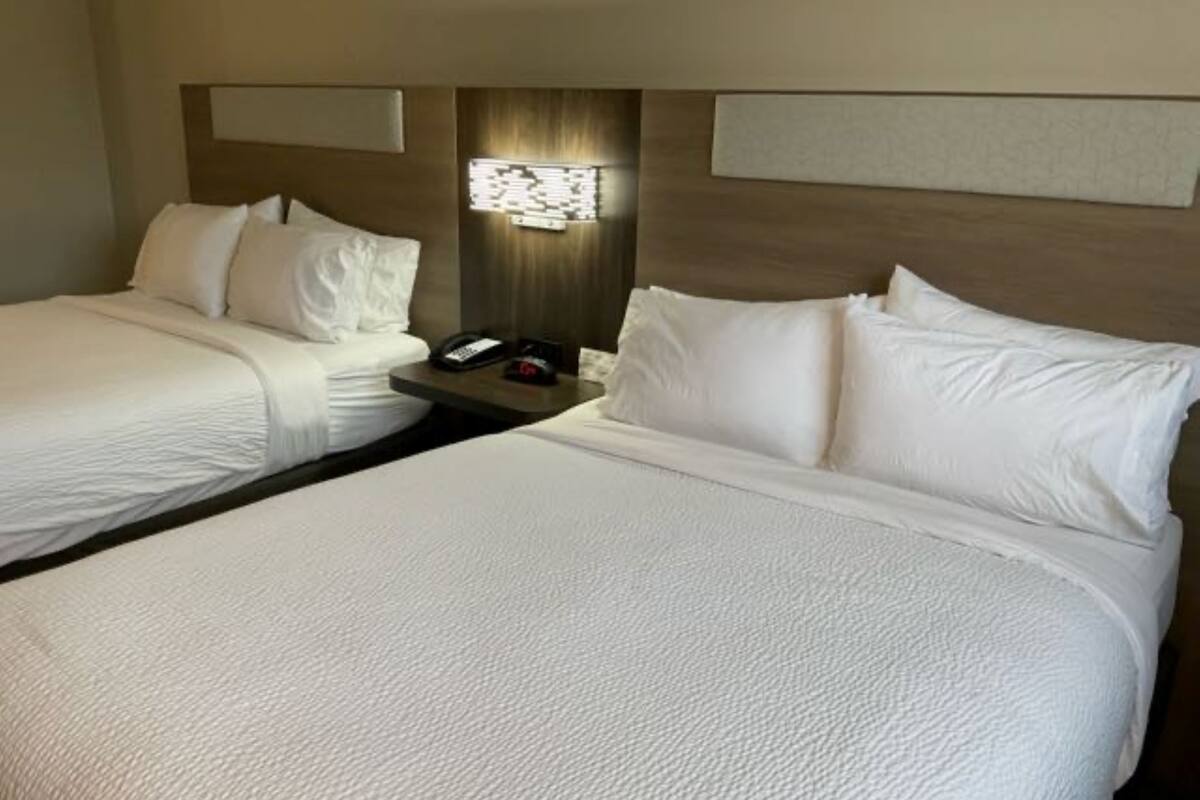 Une chambre d’hôtel avec deux lits, une table de chevet, un téléphone et un luminaire fixé au mur.