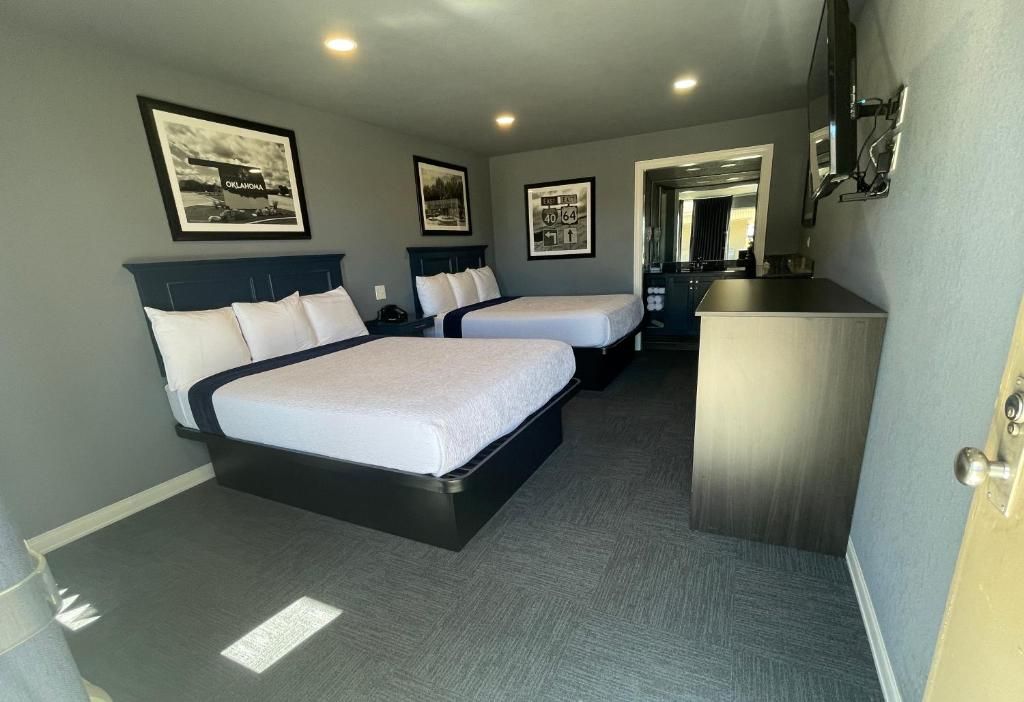 A hotel room with two beds, a desk, and a mirror.