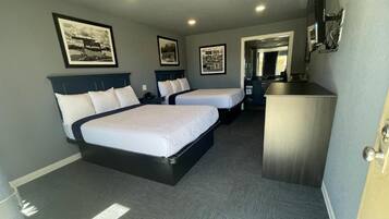 A hotel room with two beds, a desk, and a mirror.