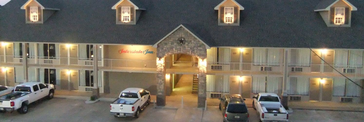 A hotel with a central entrance, multiple parking spaces, and a sign reading "Interstate Inn".