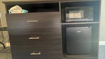 A dark wooden cabinet with drawers and a microwave on top.