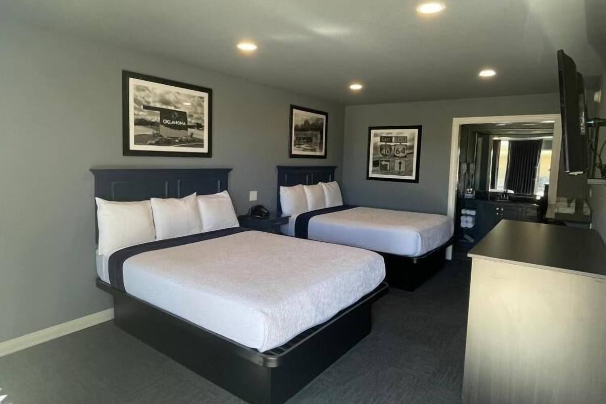 A hotel room with two beds, a desk, and a mirror.