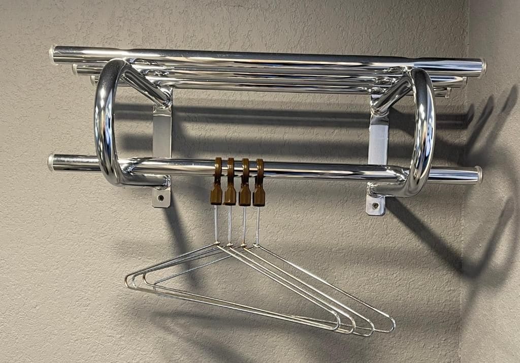 Ein chromfarbener Metallkorb mit einem hängenden Drahtkorb und vier braunen Flaschenkappen.