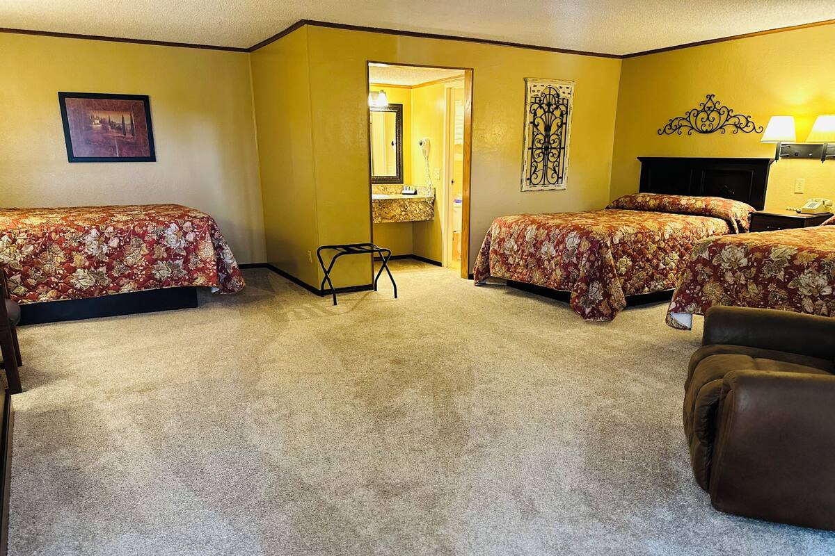 A hotel room with two beds, a chair, a desk, and a mirror.