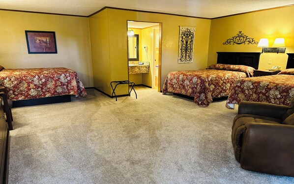A hotel room with two beds, a chair, a desk, and a mirror.