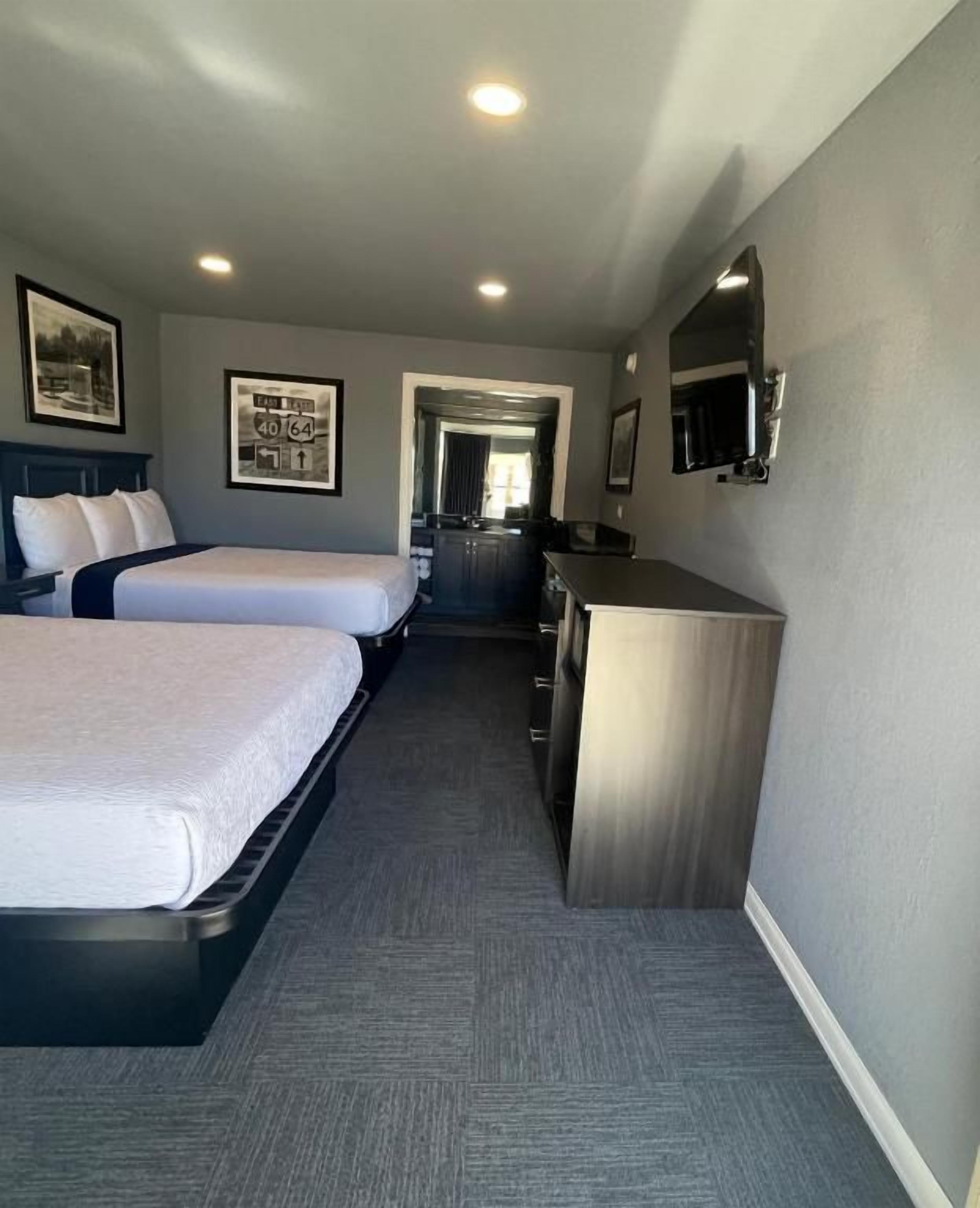 Une chambre d’hôtel avec deux lits, un bureau et un miroir.