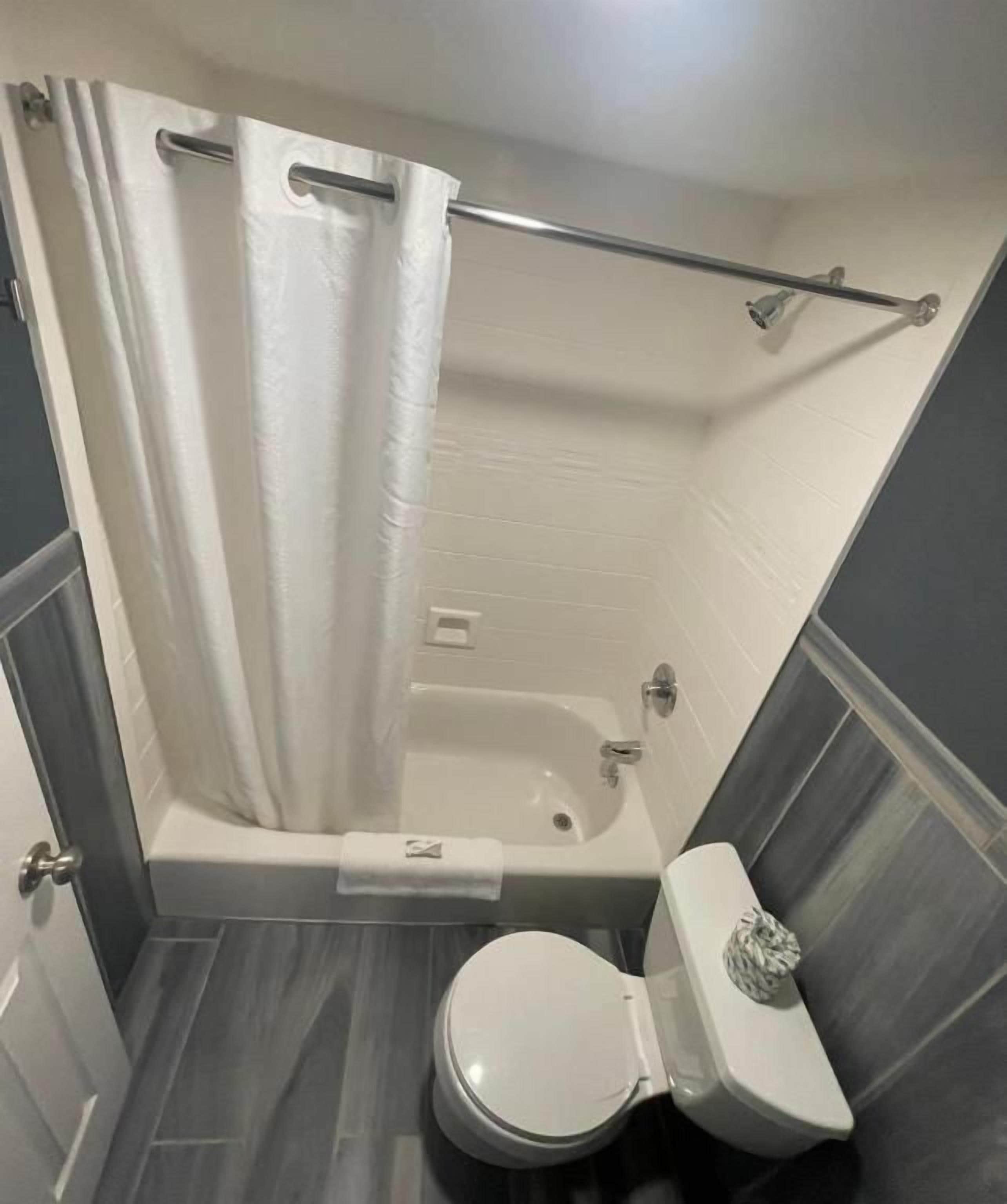 A bathroom with a bathtub, toilet, and shower curtain.