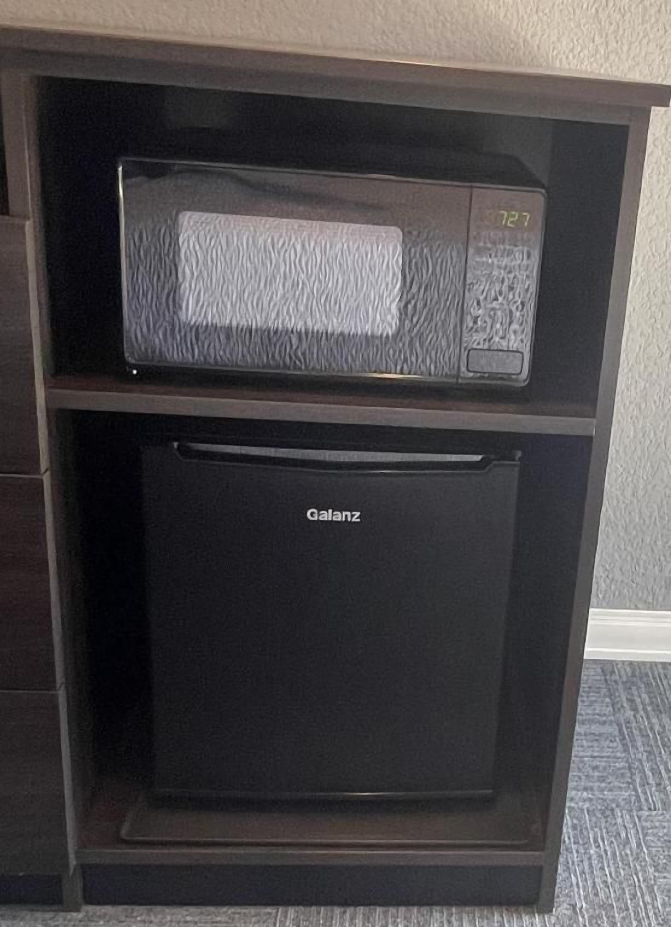 Un refrigerador negro con la marca 'Galanz' y un microondas encima.
