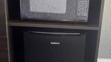 Un refrigerador negro con la marca 'Galanz' y un microondas encima.