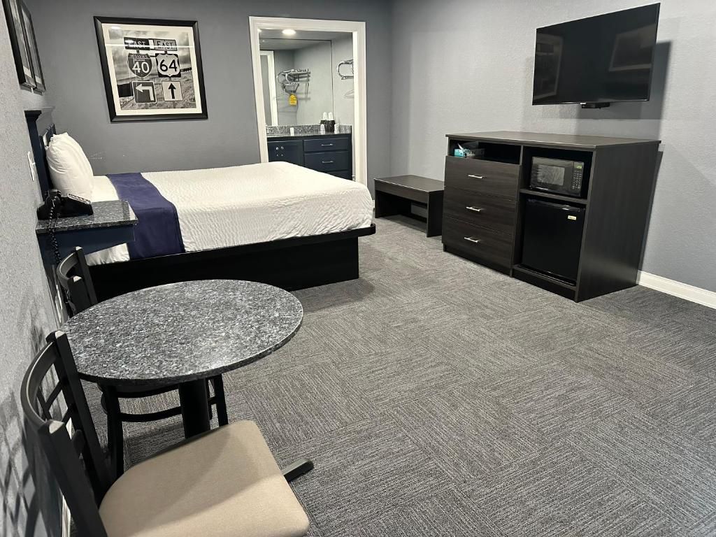 Une chambre d’hôtel avec un lit, un bureau, une chaise, un four à micro-ondes, une télévision et un panneau de signalisation encadré accroché au mur.
