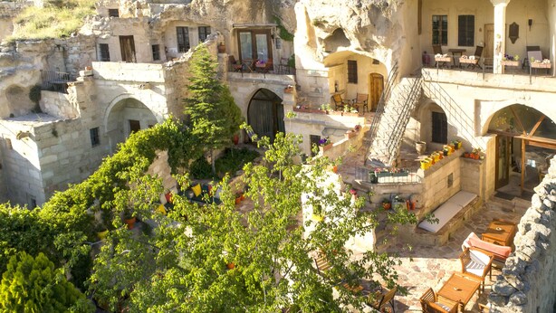 Un edificio de piedra tradicional con varios niveles, zonas de estar al aire libre y una escalera que conduce a un nivel superior.