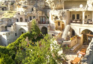 A traditional stone building with multiple levels, outdoor seating areas, and a staircase leading to an upper level. - 4 ODA Cave House Boutique Hotel (Ürgüp)