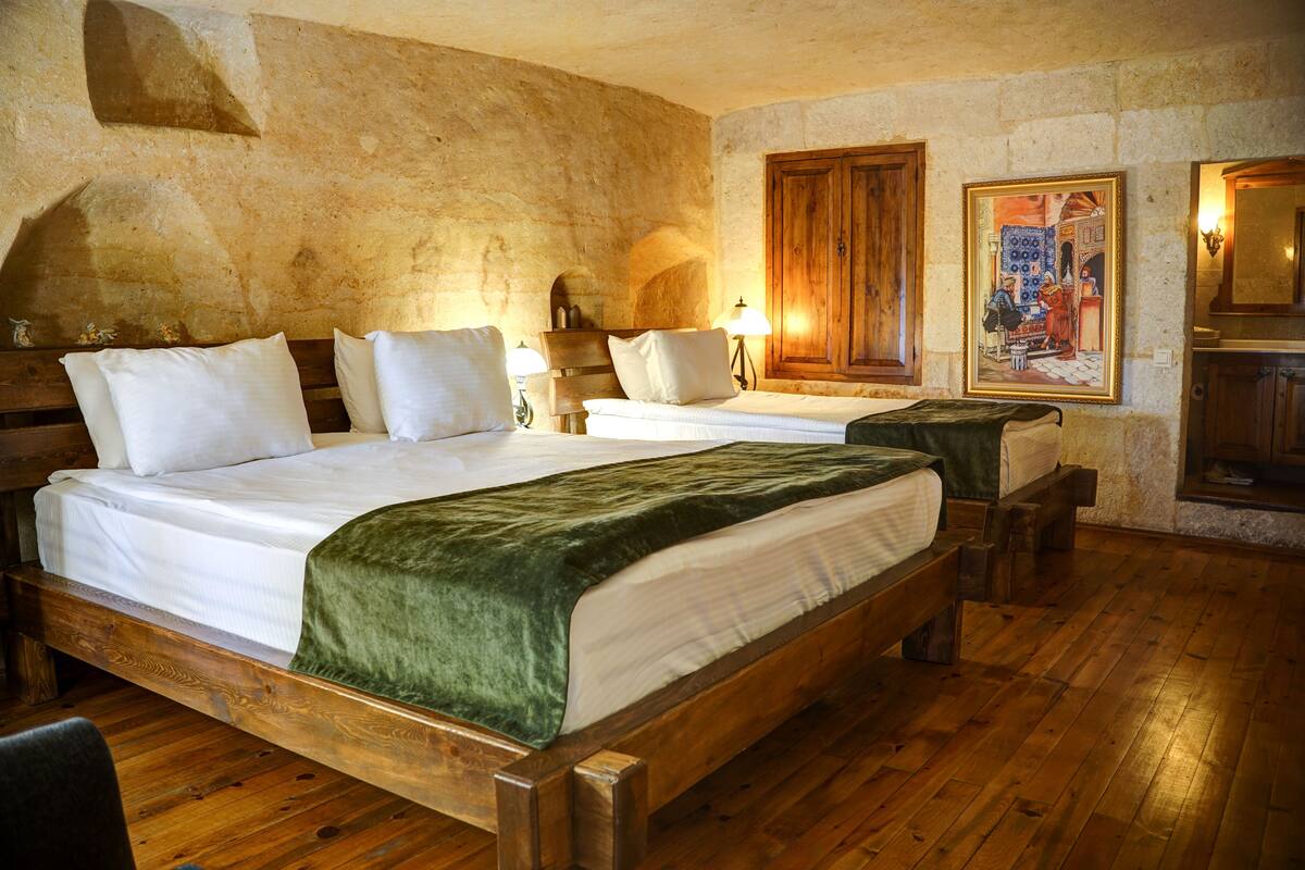 A room with two wooden beds, a stone wall, and a wooden cabinet.