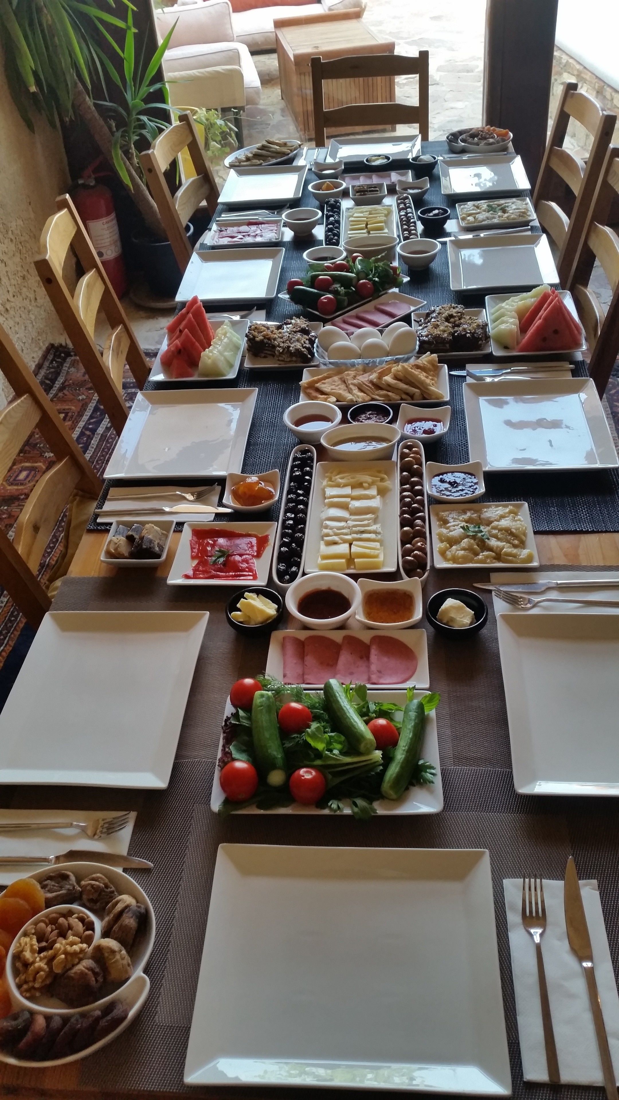 A dining table set for a meal with various dishes, including fruits, vegetables, and meats, arranged on a mat.