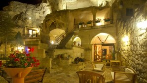 Un interior acogedor con paredes de piedra, muebles de madera y una escalera que conduce a un nivel superior.