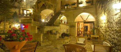 Un interior acogedor con paredes de piedra, muebles de madera y una escalera que conduce a un nivel superior.