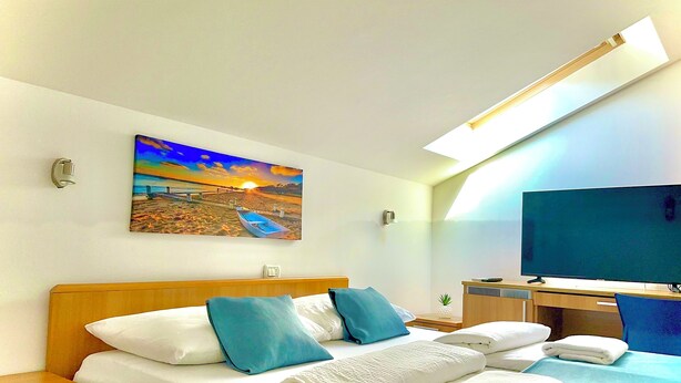 Una habitación de hotel con cama, escritorio, televisor y un cuadro de una playa.
