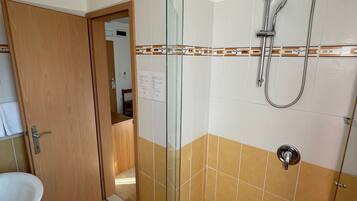 Een badkamer met een douchecabine van glas, een wastafel en een toilet.