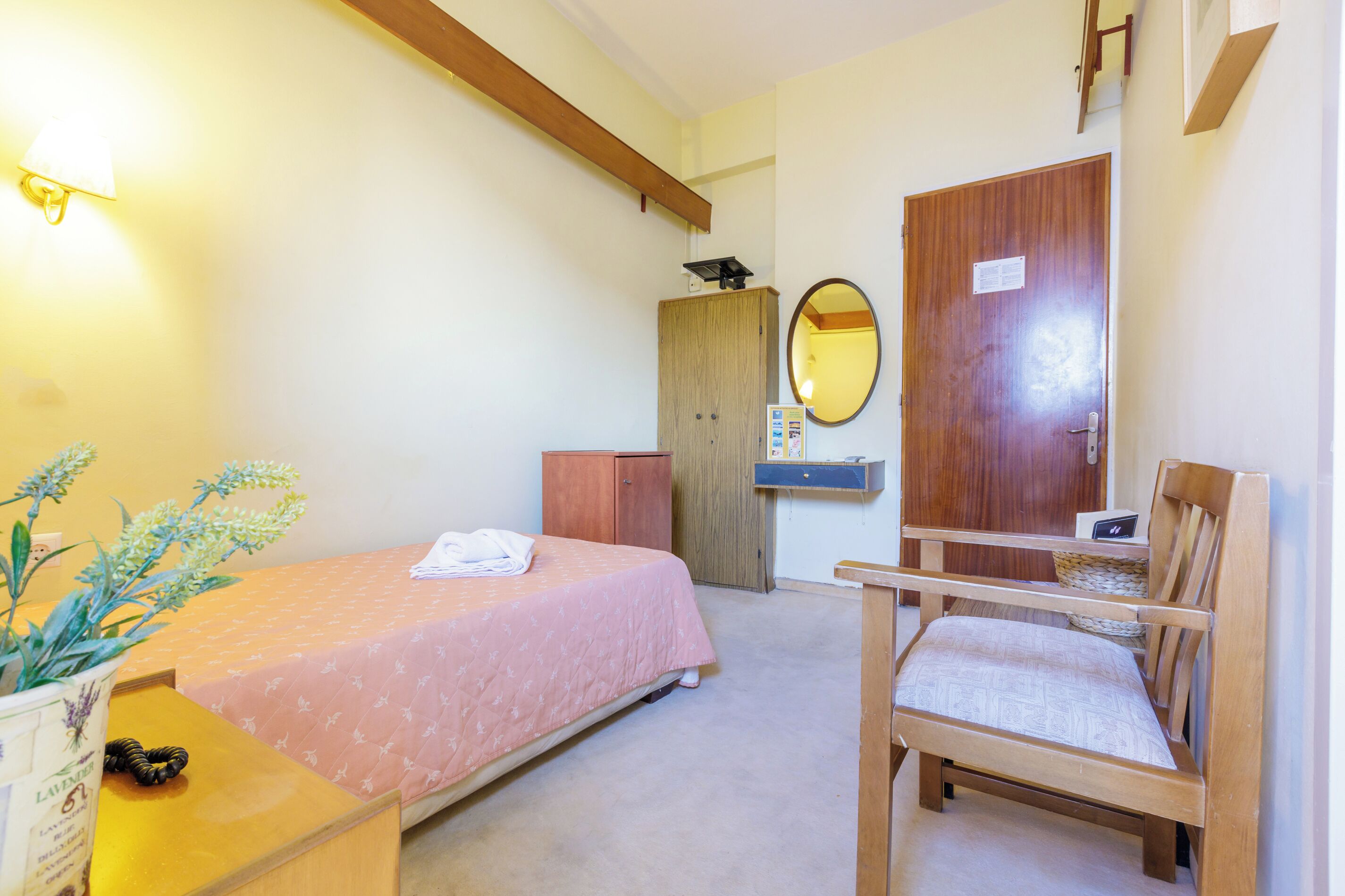 Une chambre à coucher comprenant un lit, une chaise, un bureau, une armoire et un miroir.