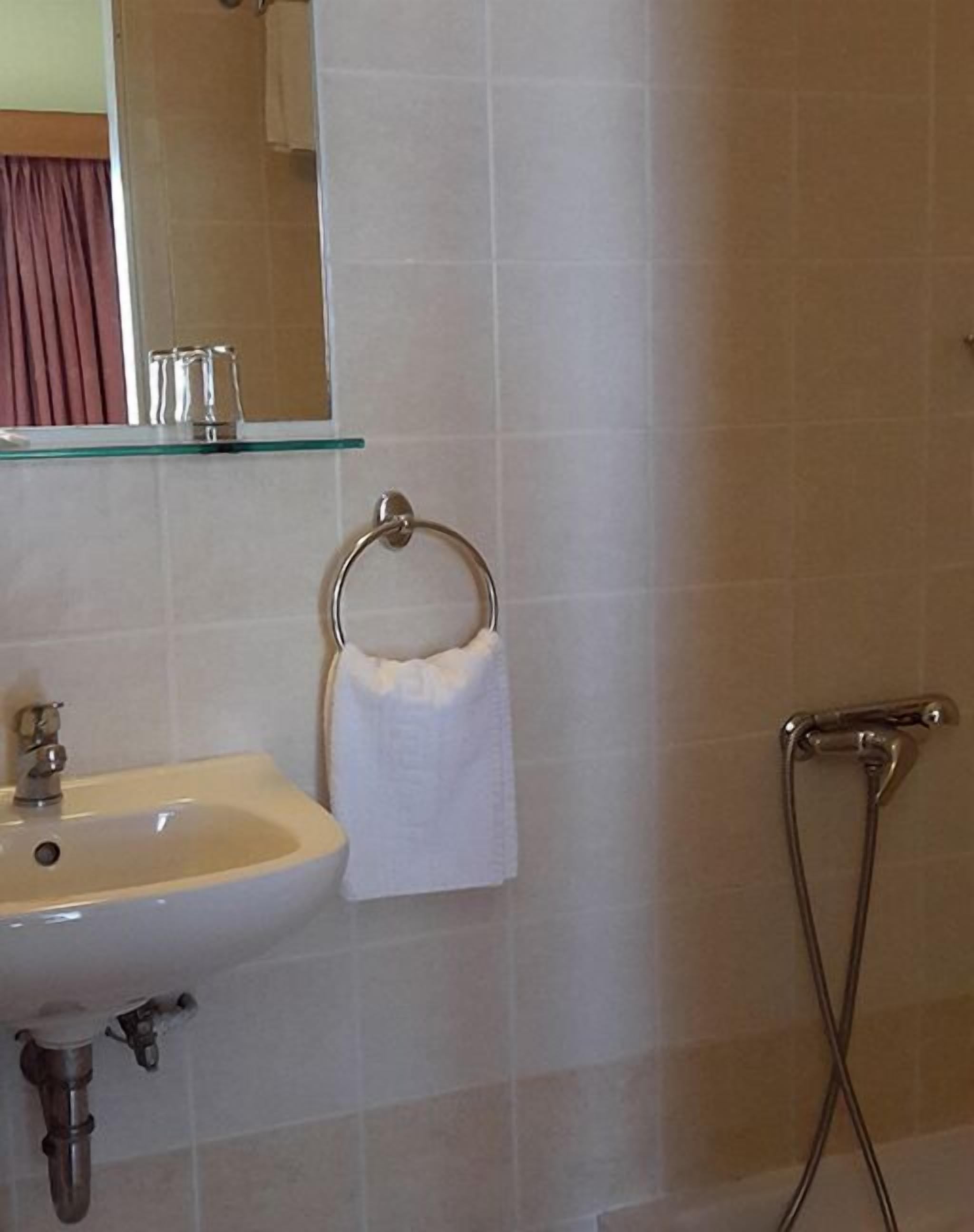Un baño con lavamanos, espejo y toallero.