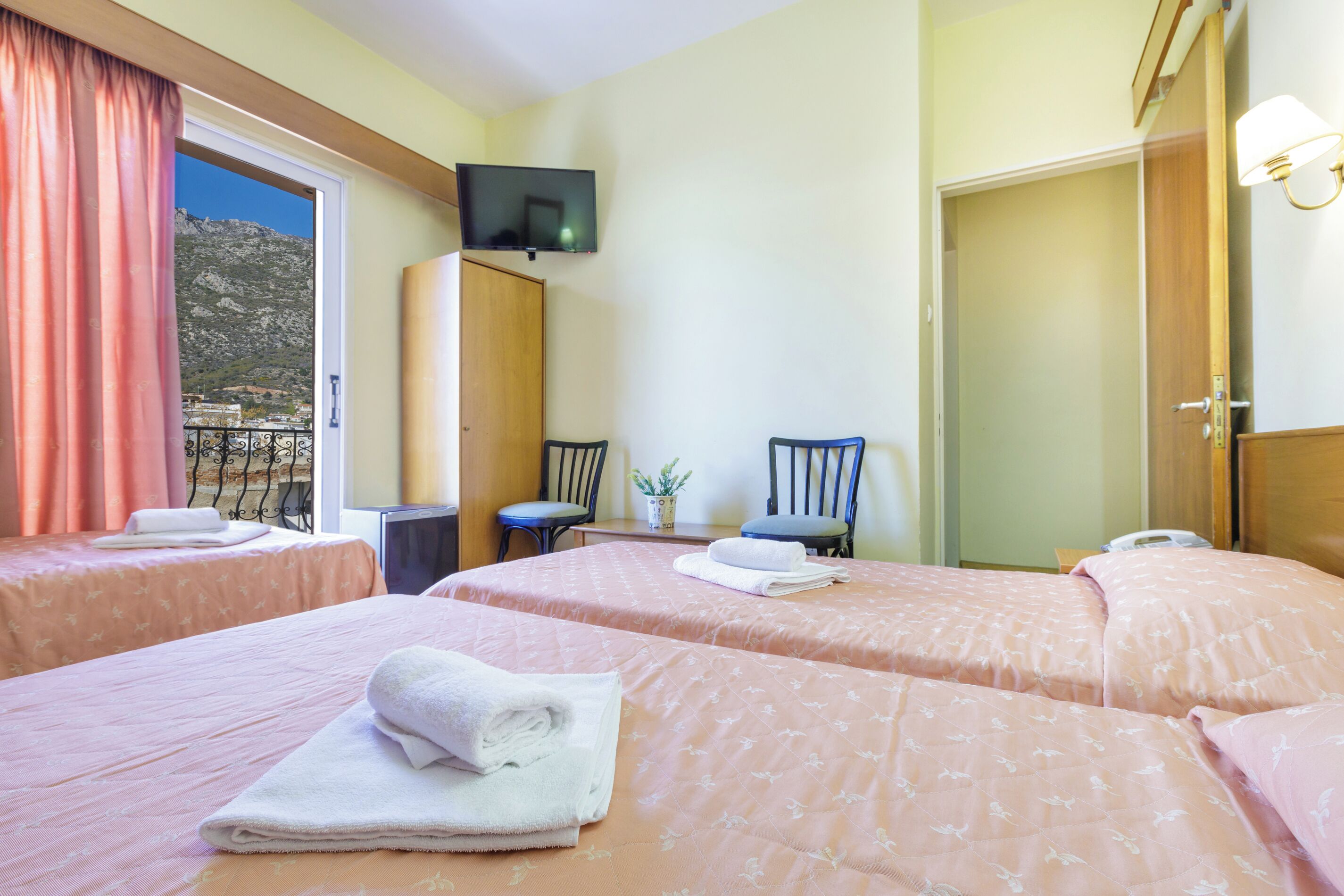 A hotel room with two beds, a TV, a desk, and a chair.